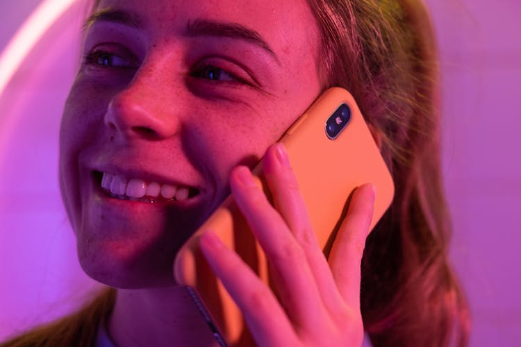 Cheerful Woman Talking On Smartphone In Neon Light