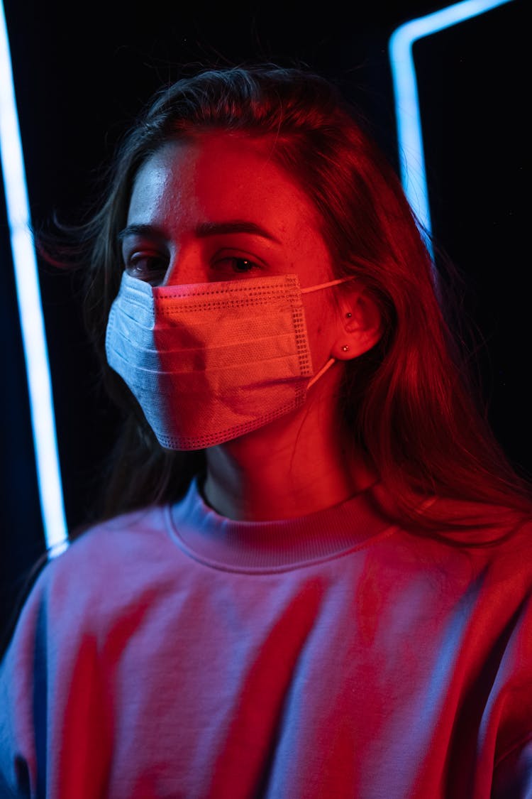 Young Woman In Protective Medical Mask Among Glowing Blue Lamps