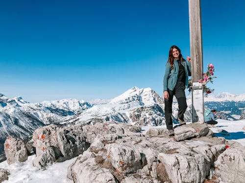 Woman Standing Beside a Pole on Mountain Top