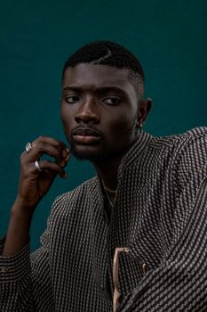 A sophisticated portrait of a man in traditional Nigerian attire against a dark background, showcasing elegance and style.