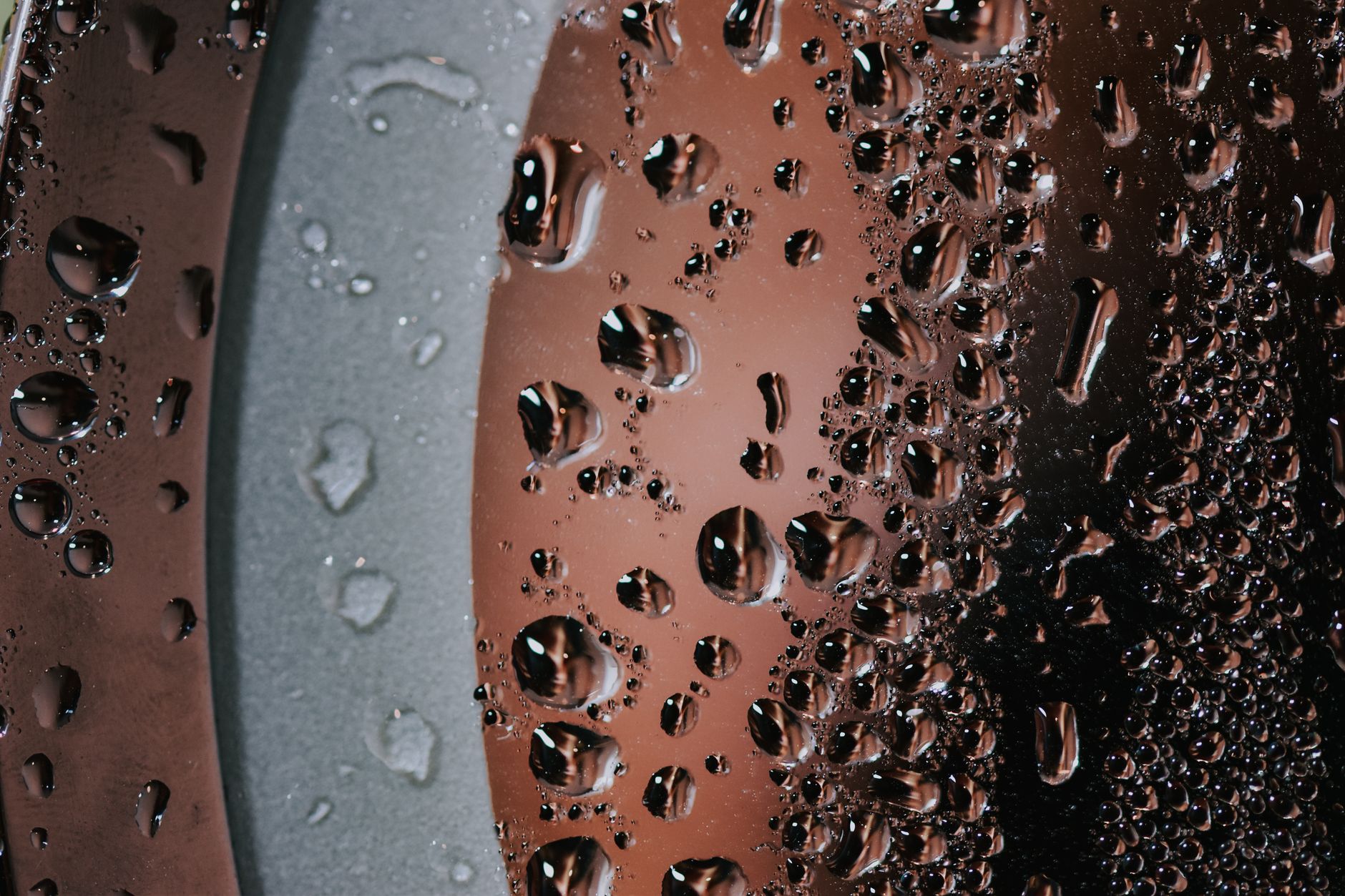 High-detail macro shot of water droplets on a glass surface with round edges.