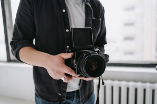 Free A person holding a vintage professional film camera indoors with natural light. Stock Photo