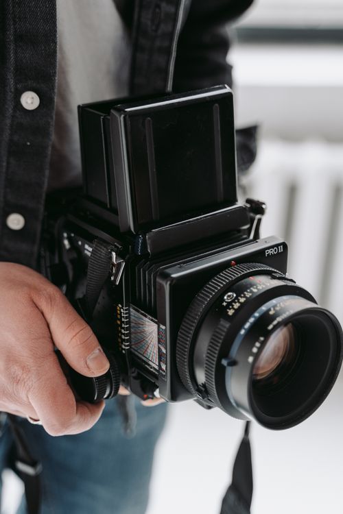Free A man holding a vintage medium format camera, showcasing classic photography equipment. Stock Photo