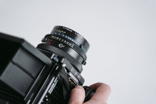Free Detail shot of a classic film camera held by a person, showcasing its lens and build. Stock Photo