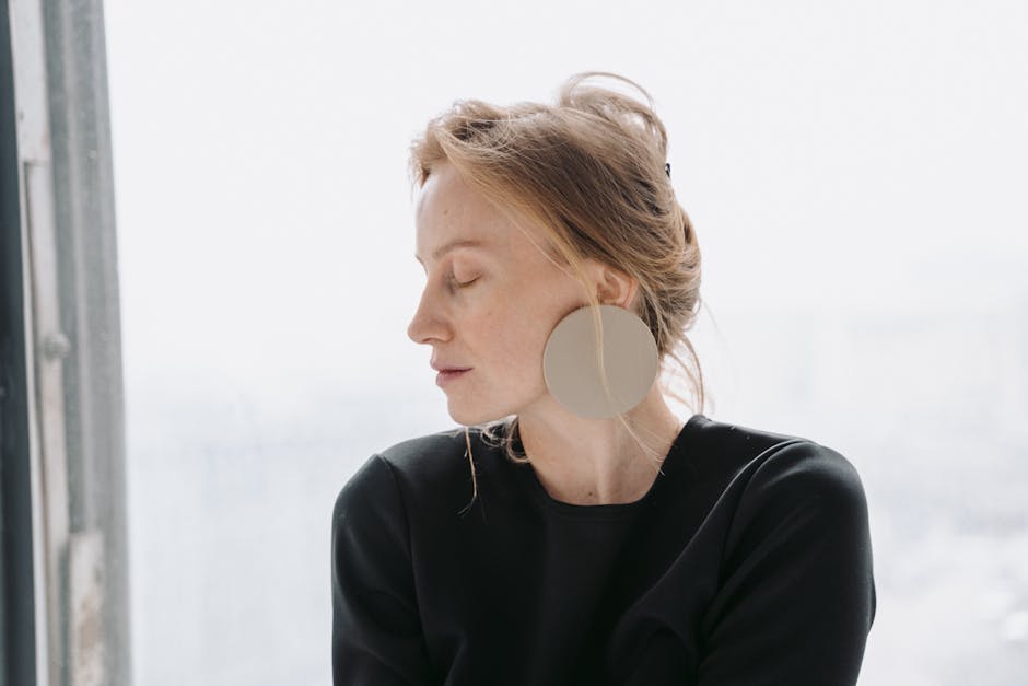 A serene side profile of a woman with eyes closed, wearing a black outfit and large earrings.