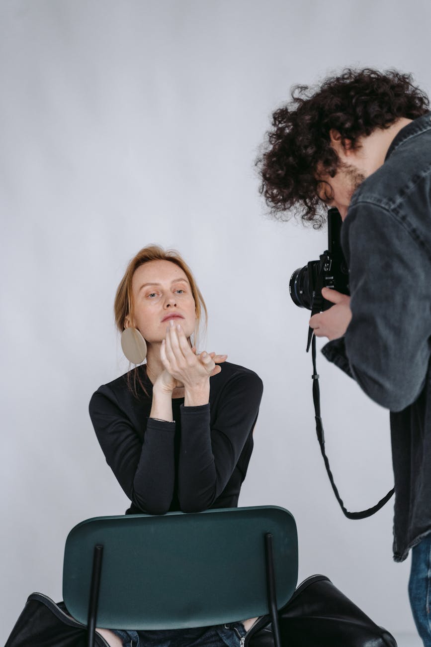 A woman poses for a photoshoot as a photographer captures the moment.