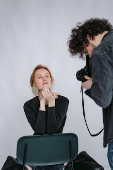 A woman poses for a photoshoot as a photographer captures the moment.