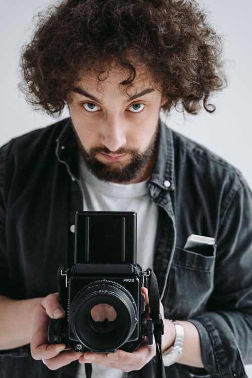 Free Young male photographer holding a vintage camera, ready to capture moments. Stock Photo