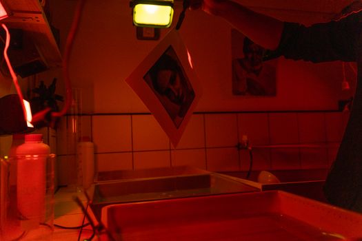 Photograph of a film being developed in a darkroom with red lighting.