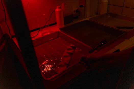 Darkroom scene with film developing in red light, creating a vintage feel.