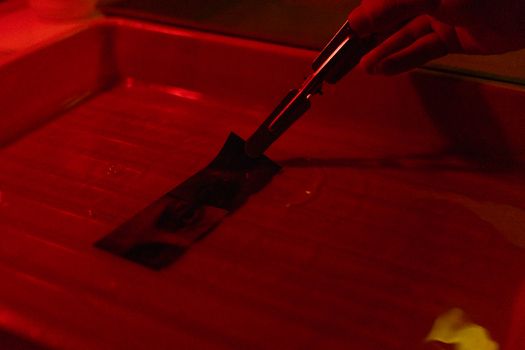 Close-up view of film developing in a darkroom with red lighting.