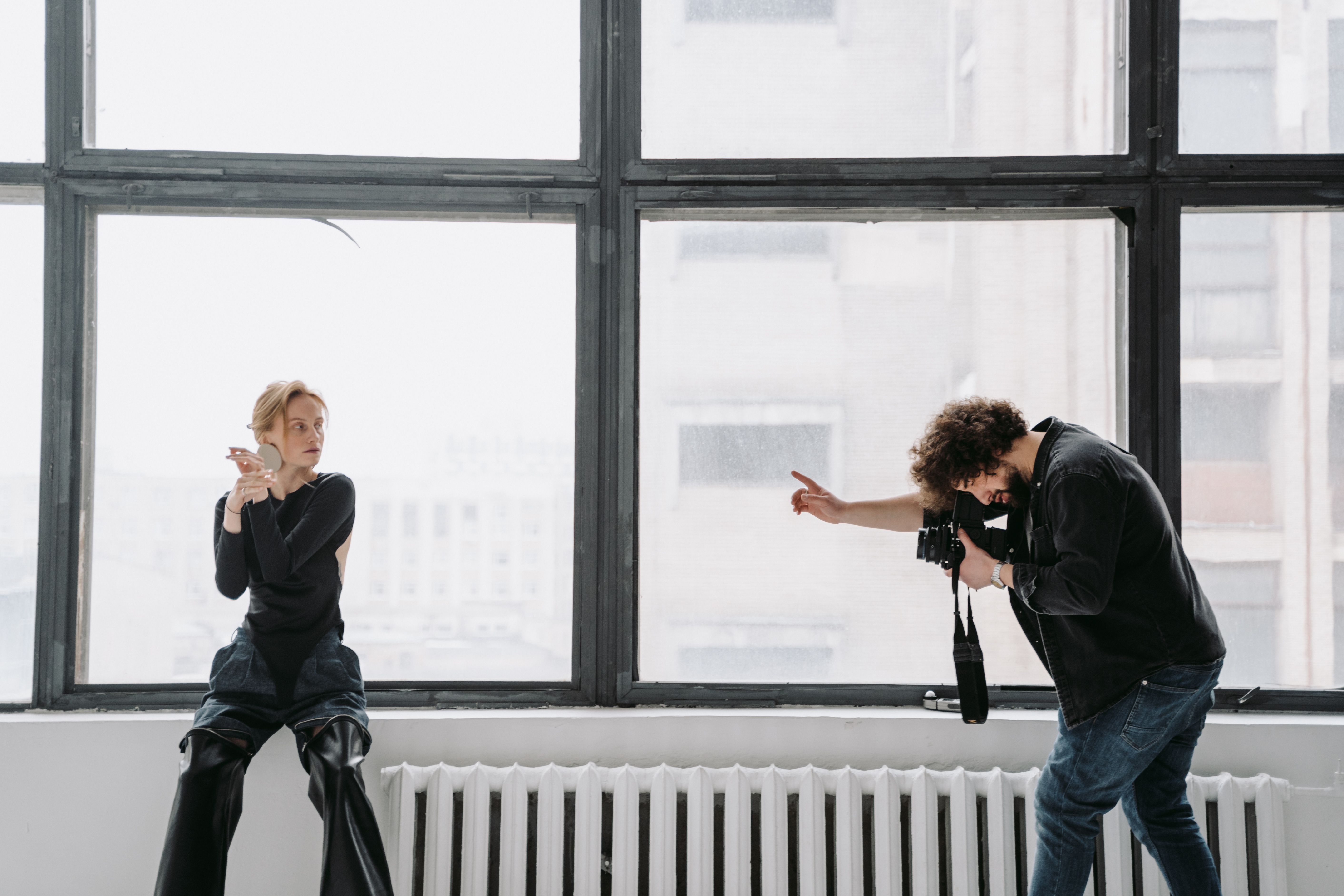 Model posing in a bright studio while a photographer captures the moment with a professional camera.