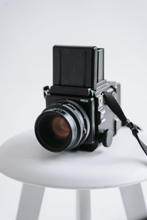 Free Close-up of a vintage film camera placed on a white stool, showcasing its classic design. Stock Photo