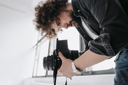 A photographer focuses intently using a vintage film camera indoors. Capturing creativity.