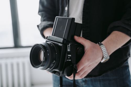 Free Close-up of a vintage film camera held by a person, showcasing classic photography equipment. Stock Photo