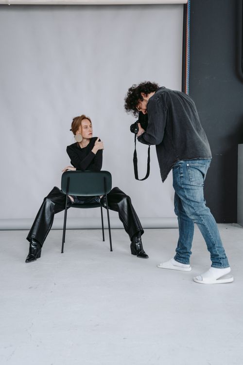 Free A professional photoshoot in a studio with a model posing on a chair. Stock Photo