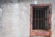 Exterior of abandoned aged shabby building and rusted window bars on gray wall in daylight