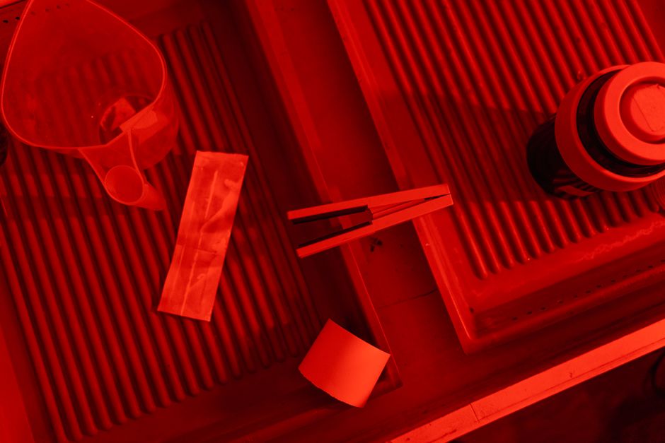 Interior de laboratório de revelação analógica com luz de segurança âmbar e bandejas de químicos