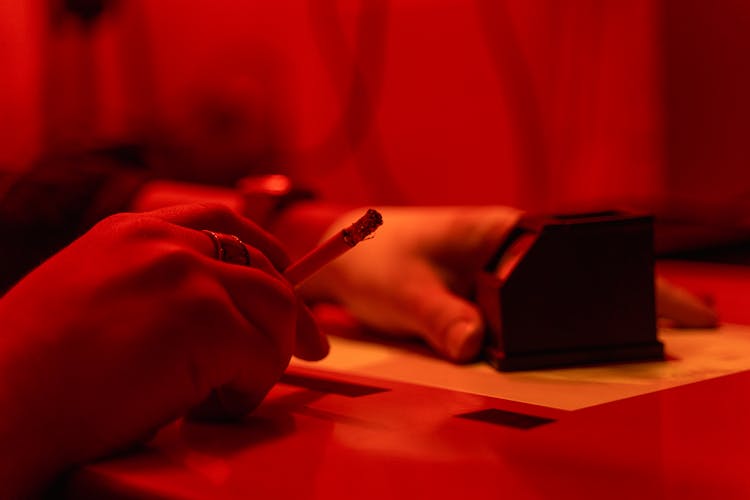 A Person Holding A Lighted Cigarette And Ash Tray