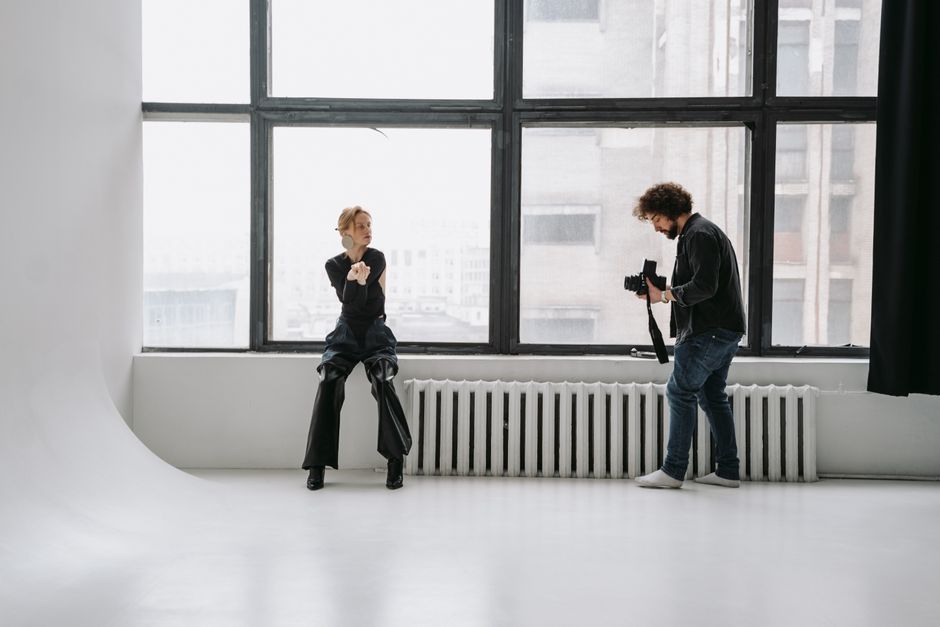 Photographer capturing model posing in bright, minimalist studio.