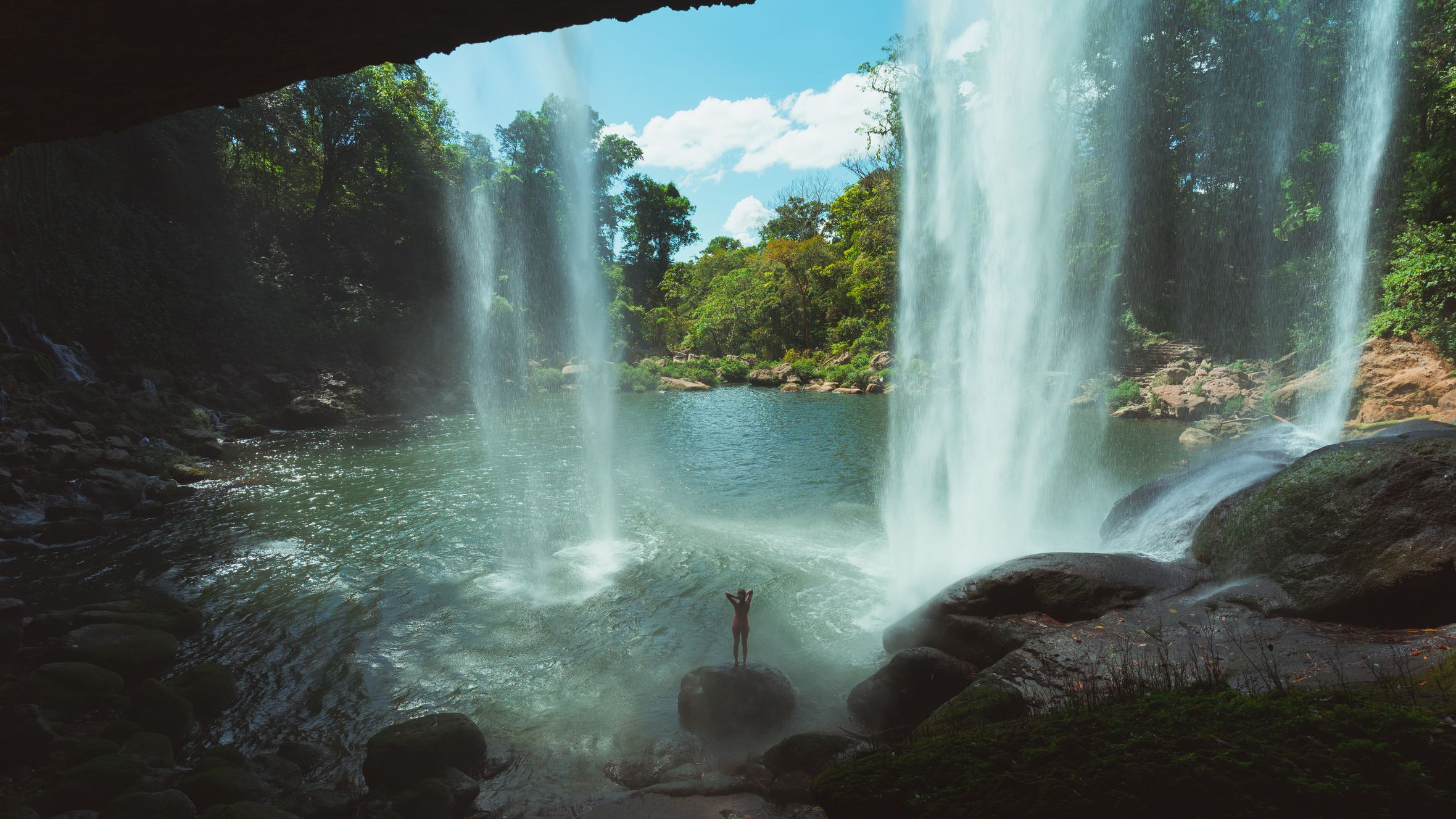 A breathtaking view of a waterfall cascading into a plunge pool within a lush jungle environment.