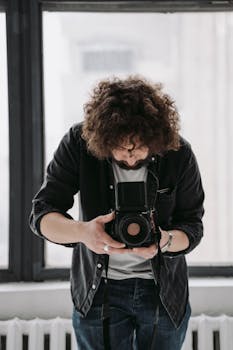 Young photographer using a vintage camera for creative snapshots indoors.