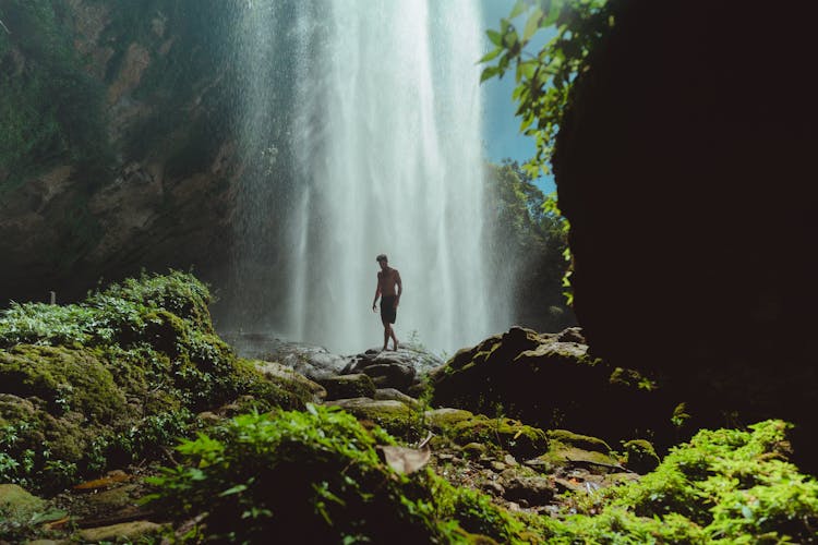 Man Standing On Rock Near Waterfalls