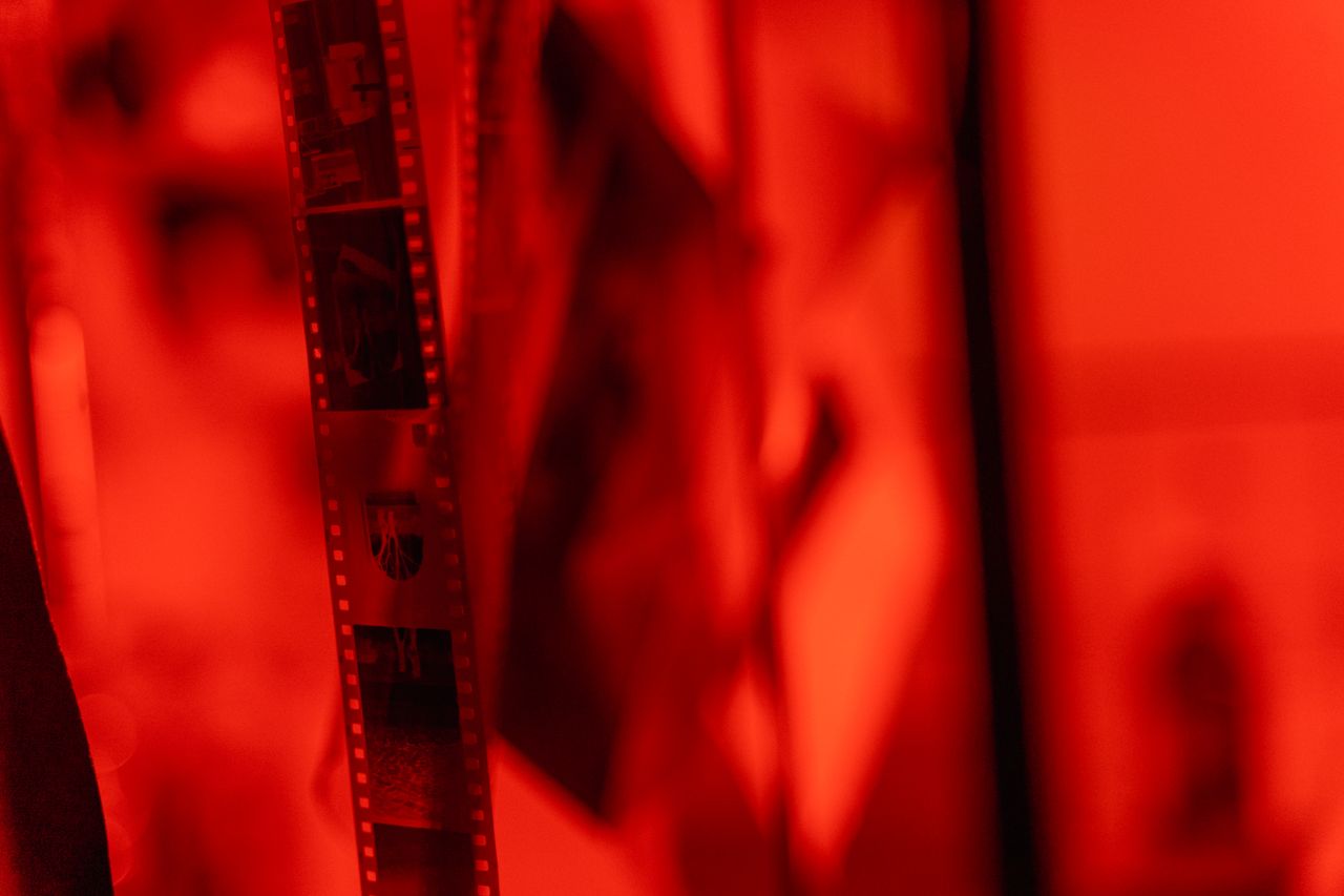 close up view of film negatives hanging in a darkroom under red lighti