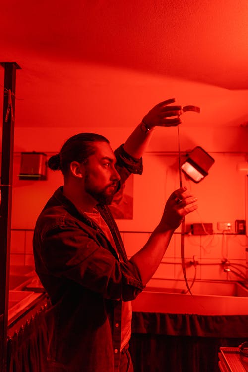 A Man Holding a Strip of Film in the Dark Room