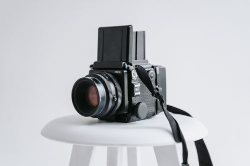 Free A professional vintage camera displayed on a simple white stool in a studio setting. Stock Photo