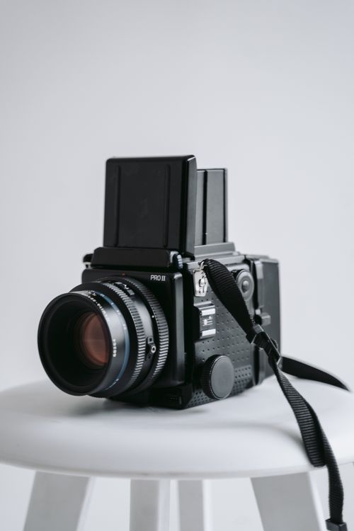 Free Classic medium format film camera placed on a white stool with a clean background. Stock Photo