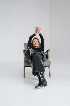 A woman elegantly reclining on a chair in a minimalistic studio setting.