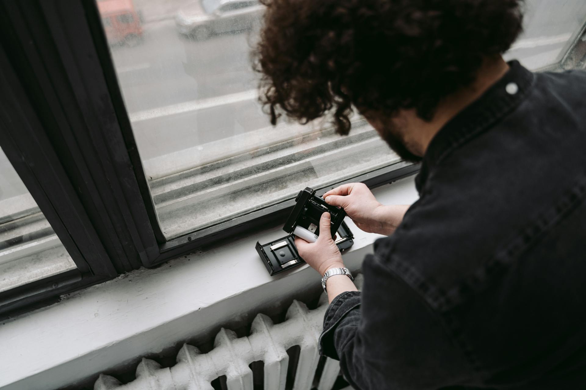 A Person in Black Jacket Holding a Camera Film Cartridge