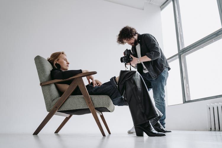 A Photographer Shooting A Woman Reclining In An Armchair