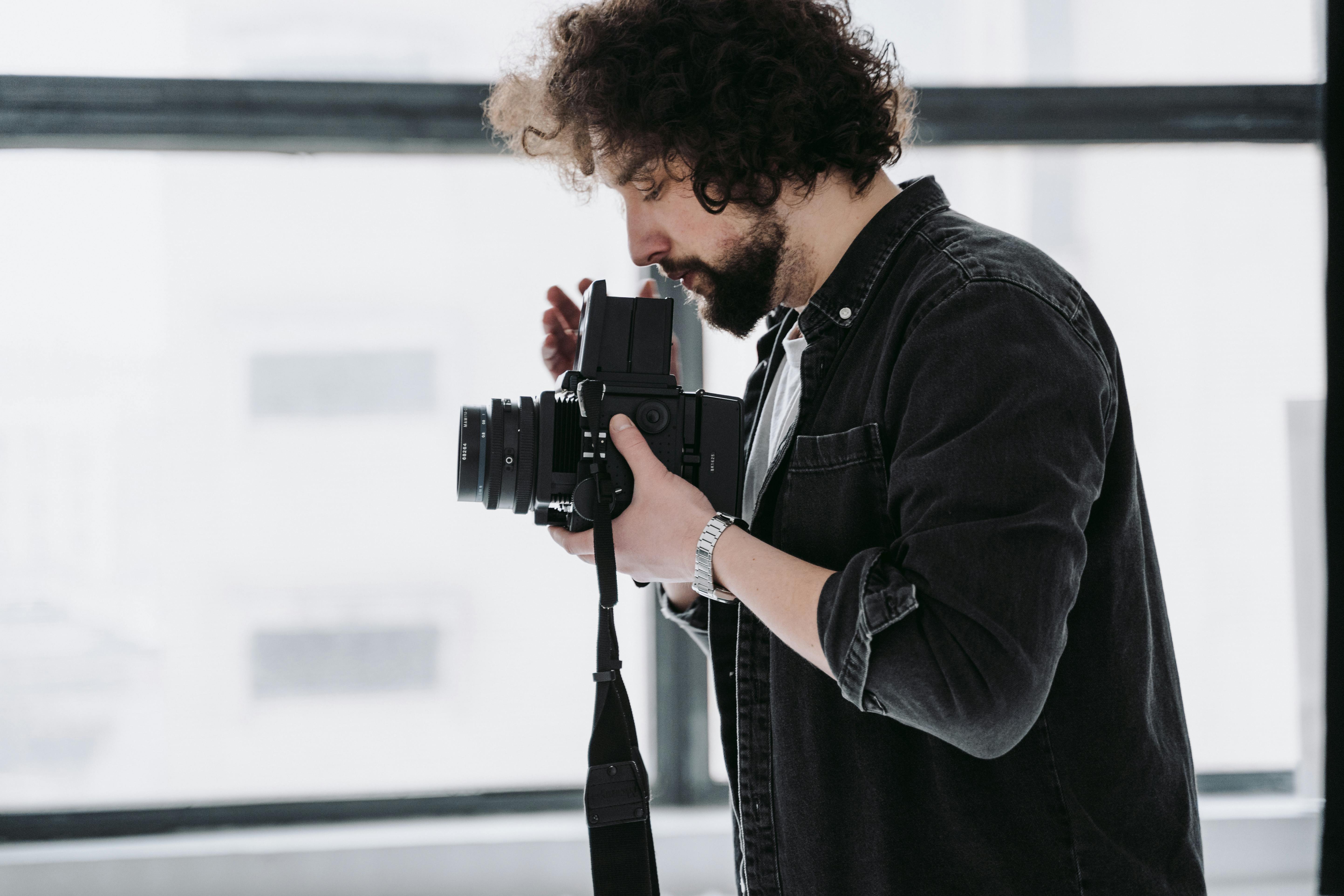 man in black jacket holding black dslr camera