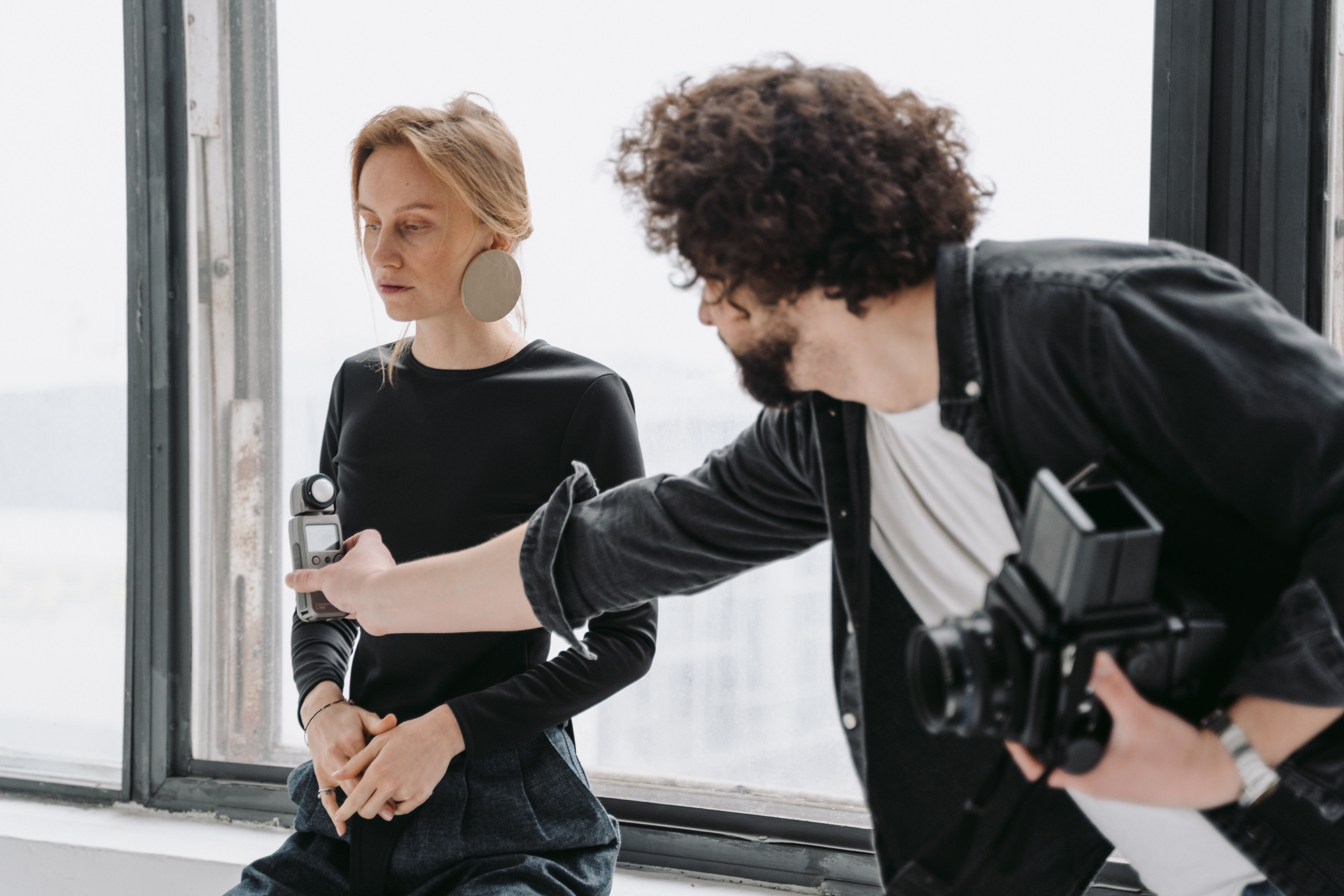 A photographer adjusts settings during a professional indoor photoshoot with a model.