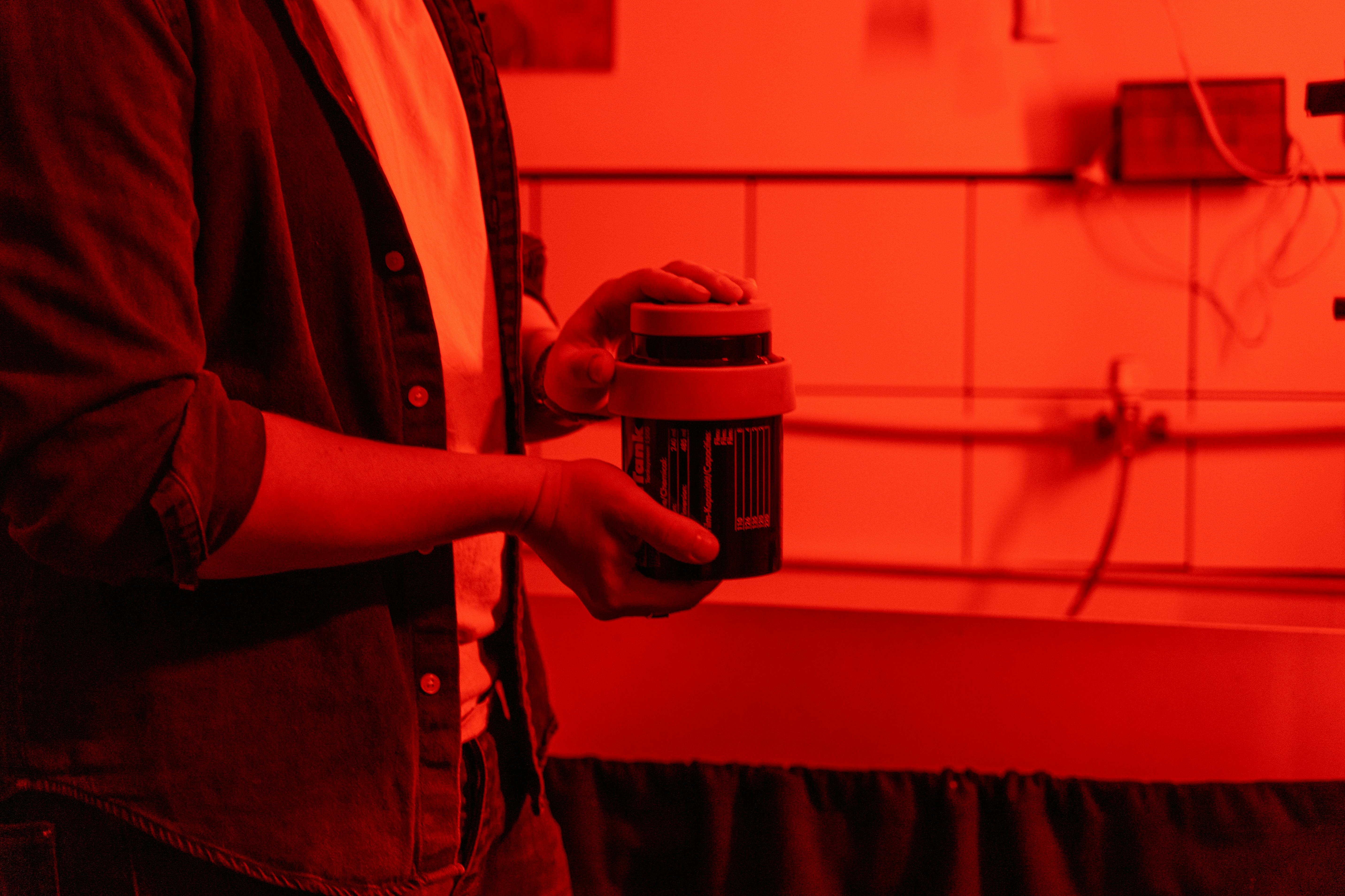 man in white button up shirt holding black and red labeled can