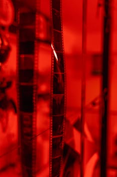 Close-up of film strips hanging in a red-lit darkroom for photo development.