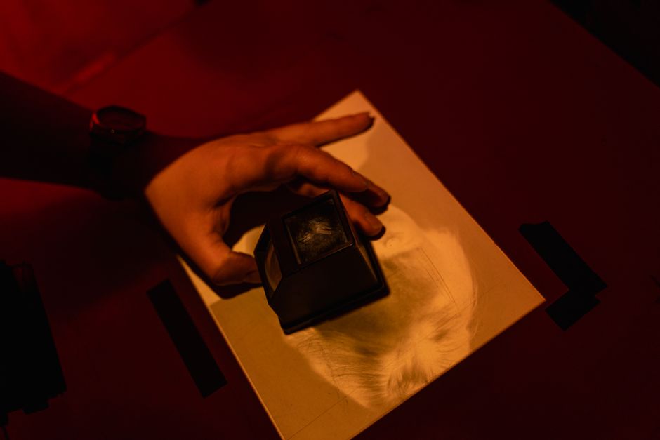 different types of engraving techniques - Person examining photo with magnifying glass under darkroom red light.