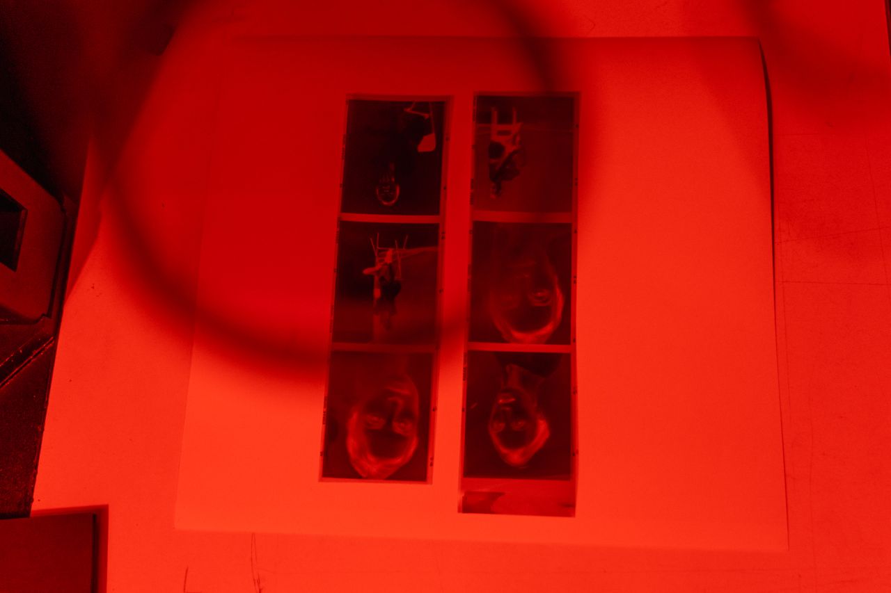 close up of film strips under red light during photography print devel