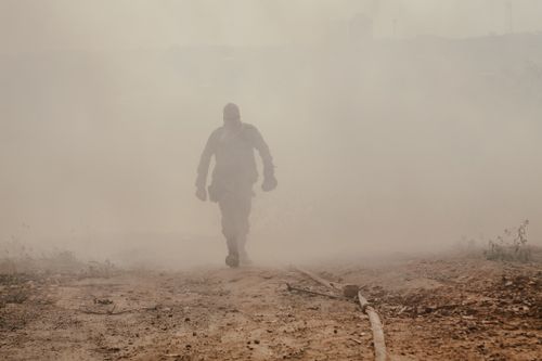 Free Silhouette of a soldier walking through dense smoke in a barren landscape, exuding bravery and mystery. Stock Photo