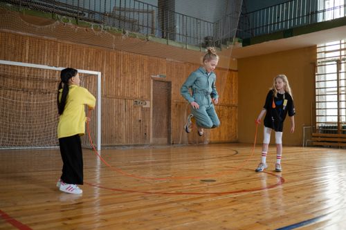 Free Children having fun with a jump rope during a play session in an indoor gym. Stock Photo