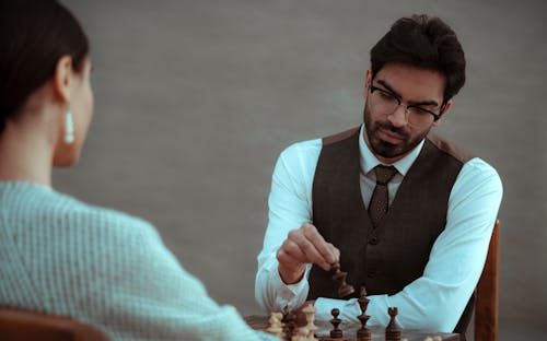 Free Serious ethnic man making move with chess figure Stock Photo