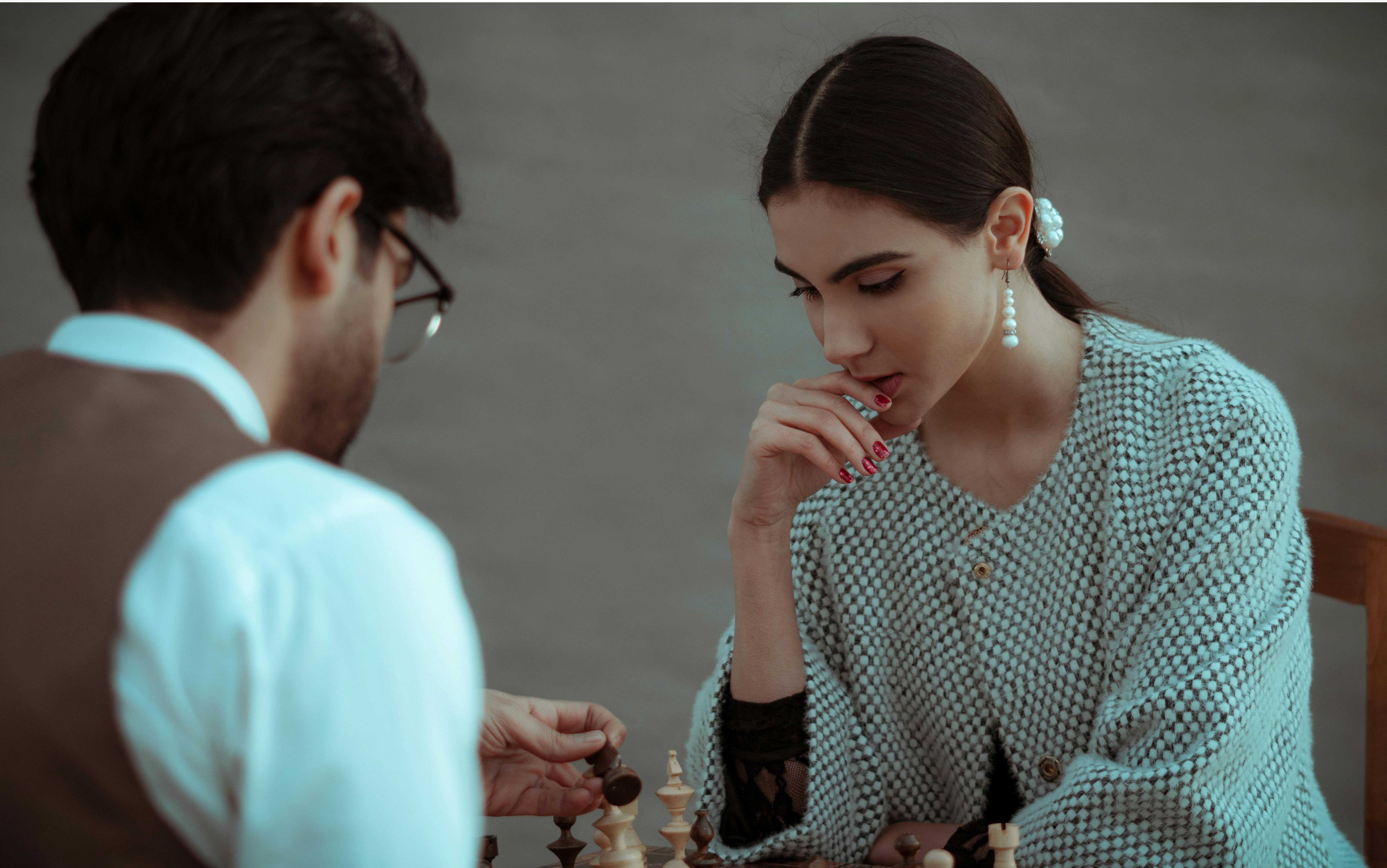 concentrated ethnic woman playing chess with male partner