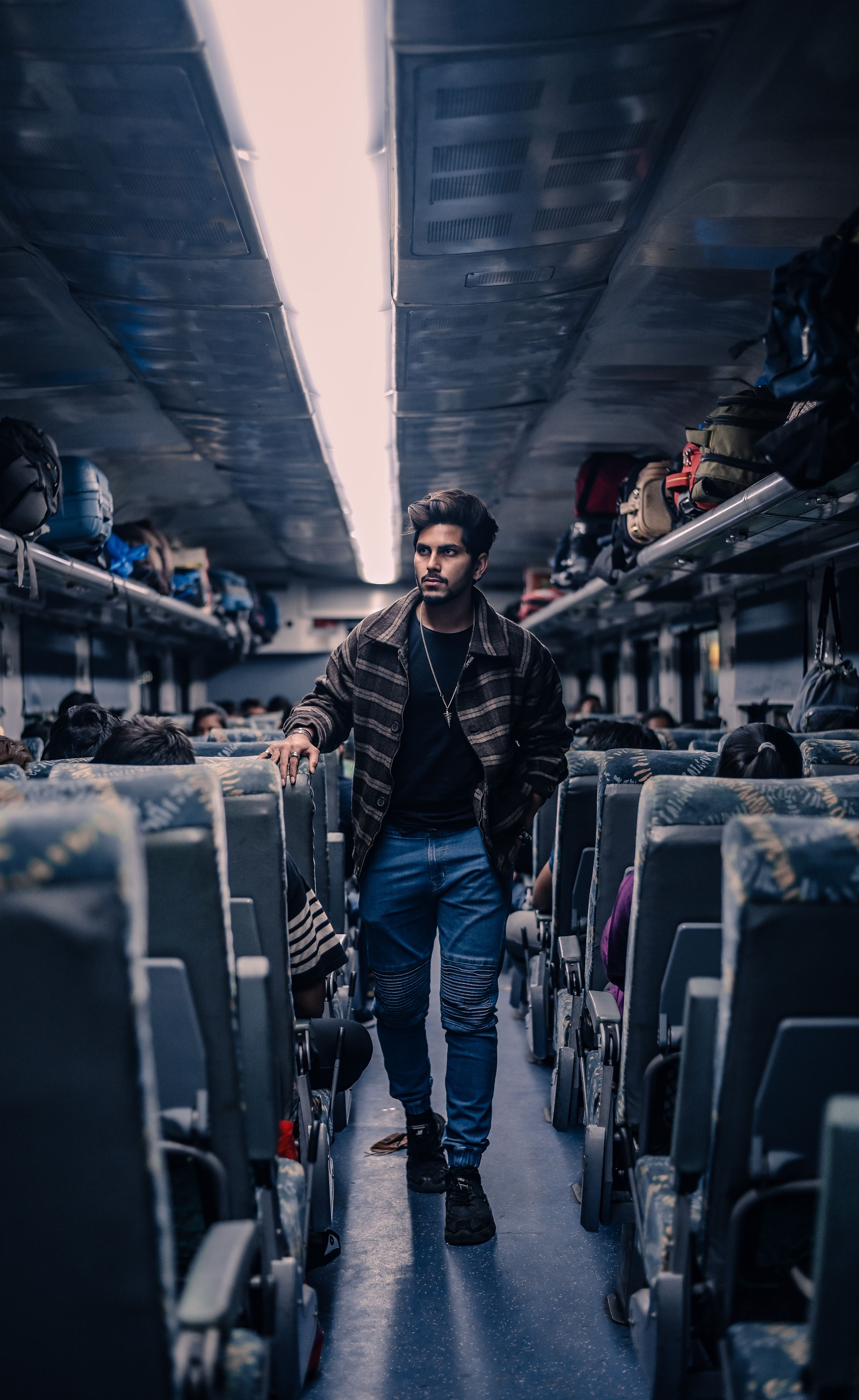 A young man walks through the aisle of a passenger train, showcasing modern public transportation.