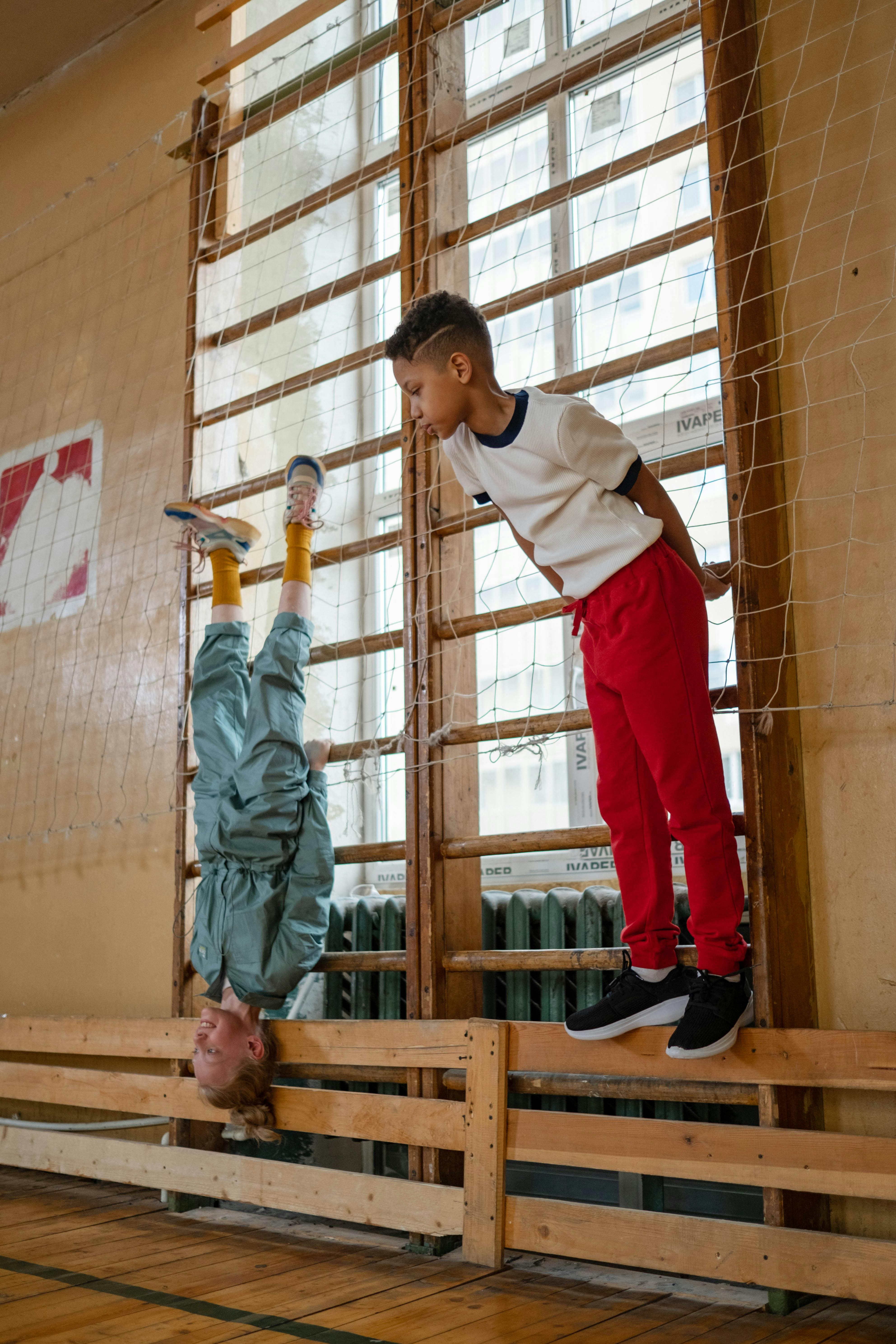 Children energetically playing in a school gym, showcasing physical skills and spontaneity.