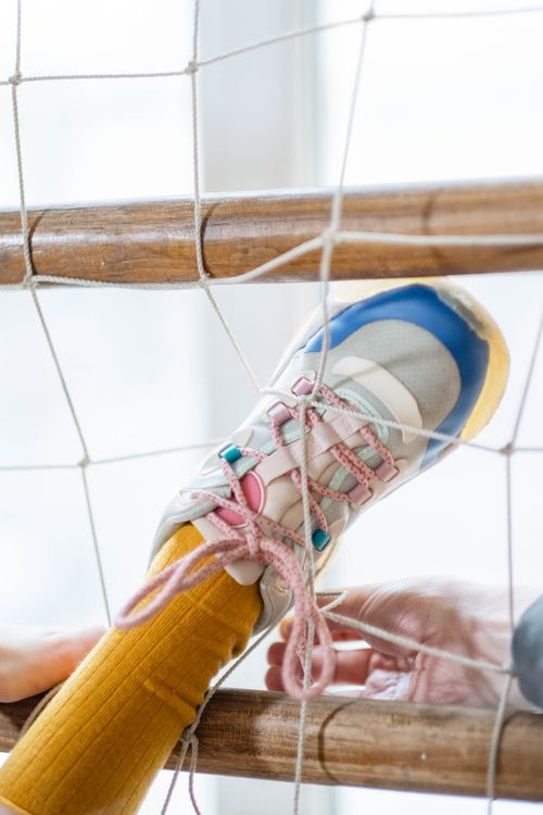 Free Close-up of a foot in a colorful shoe caught in a net, symbolizing entrapment. Stock Photo
