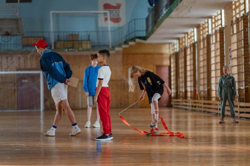 Free Children practicing gymnastics in a sports hall with their teacher. Stock Photo