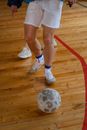 A Person in White Shorts and White Nike Sneakers Standing on a Brown Wooden Floor