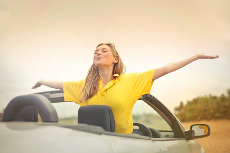 Woman Sitting On Car Under Gray Sky